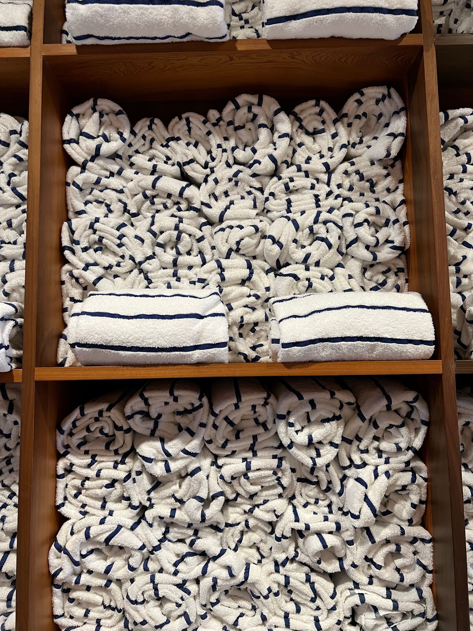 Rolled white towels on wooden shelves